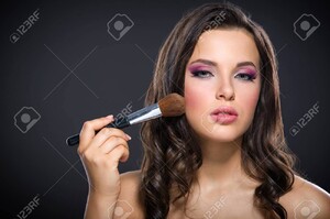 22529315-portrait-de-la-belle-fille-d-appliquer-le-maquillage-lumineux-rose-sur-fond-gris-concept-de-la-be.jpg
